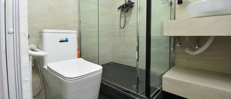 A bathroom with a toilet, a glass-enclosed shower, and a sink.