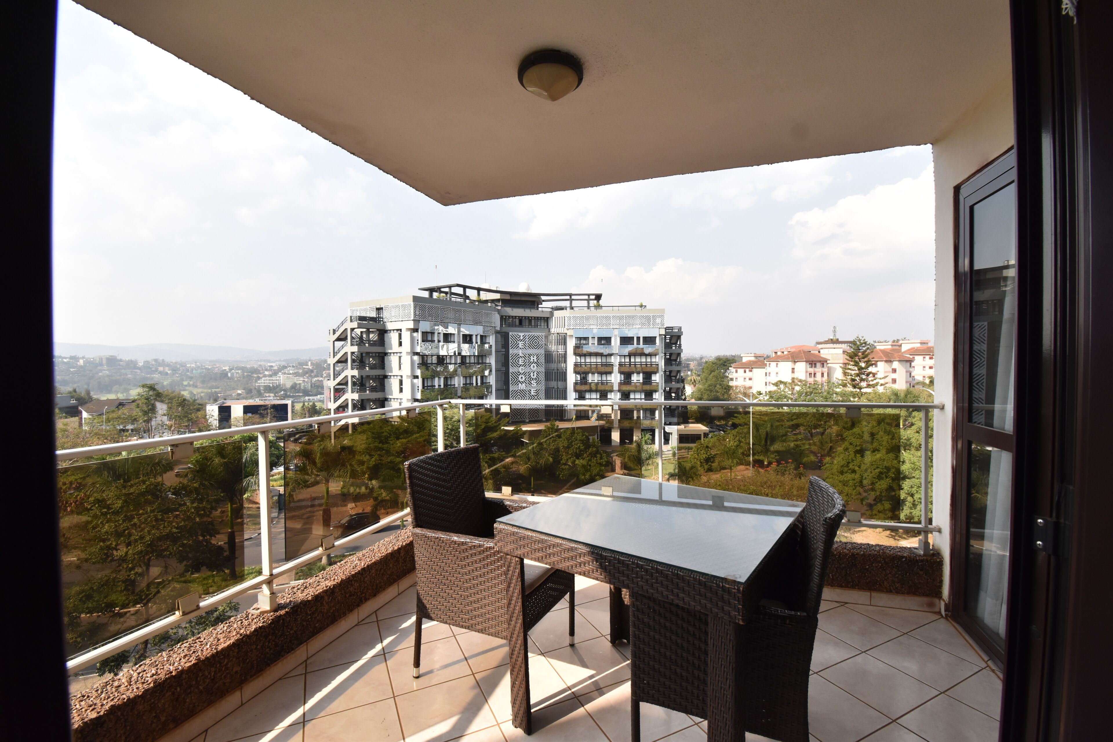 Een balkon met een tafel en stoelen, met uitzicht op een stadsgezicht vol moderne gebouwen.