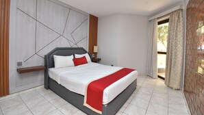 Un dormitorio moderno con cama, mesita de noche, estante en la pared y ventana con cortinas.