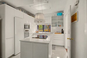 A modern kitchen with white cabinetry, a central island, and a hanging light fixture. - Vacation Home 'Bungalow Meloneras' with Sea View, Wi-Fi and Air Conditioning (Maspalomas)