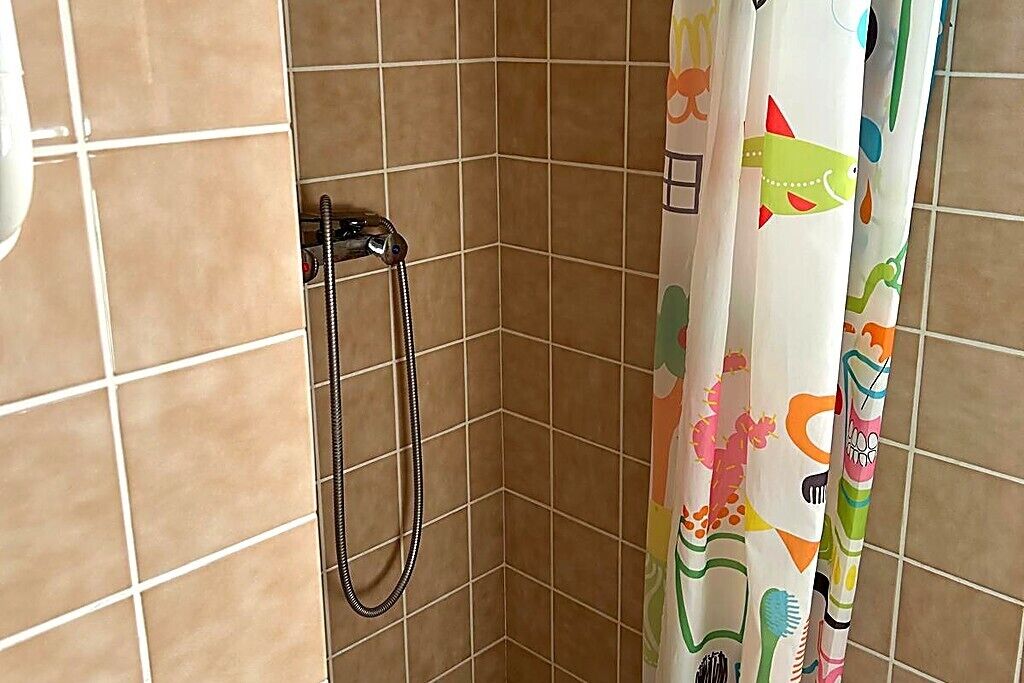 Une douche équipée d’un pommeau de douche et d’un rideau de douche aux couleurs vives.