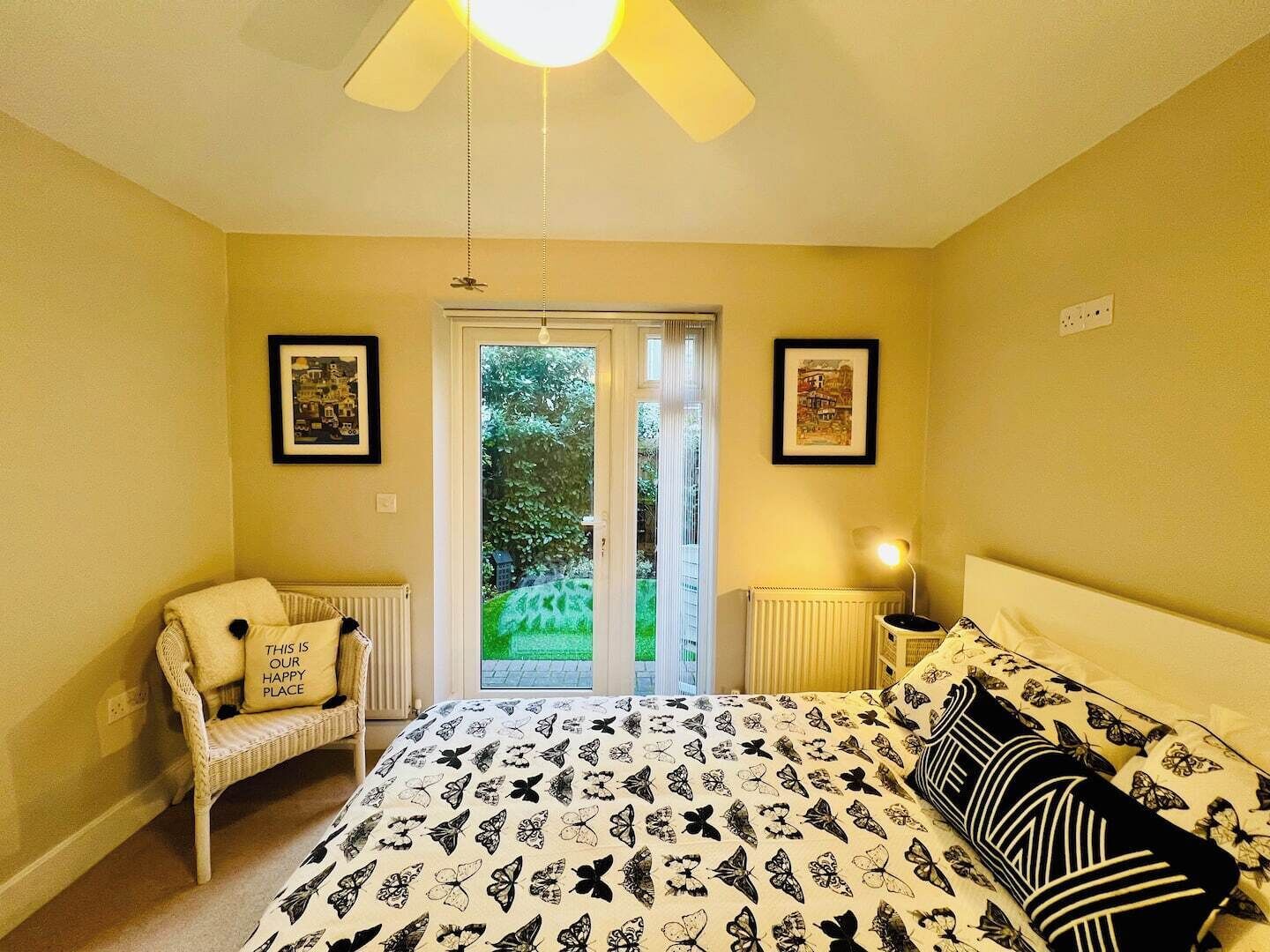 A bedroom with a bed, a chair, a radiator, a ceiling fan, and a door leading outside.