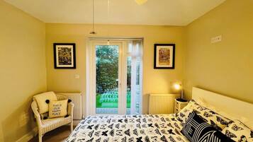 A bedroom with a bed, a chair, a radiator, a ceiling fan, and a door leading outside.