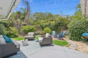 Eine Terrasse mit Gartenmöbeln, einem Grill und einem Gartenbereich mit verschiedenen Pflanzen und einem Holzzaun.