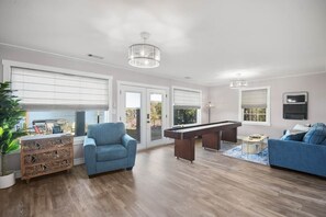 A modern living room with a pool table, blue sofas, and a wooden cabinet. - The Turtles Nest on Mulat Bay in Avalon Beach (Avalon)