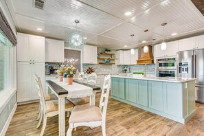 Une cuisine moderne avec des meubles blancs, un îlot central et des appareils en acier inoxydable.
