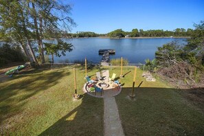 Une terrasse au bord du lac, dotée d’un foyer et de sièges, et entourée d’une clôture et d’arbres.
