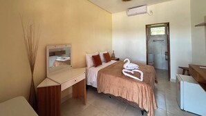 A bedroom with a bed, bedside table, mirror, and a small desk. - Pousada Caju Sansete  (Barreirinhas)