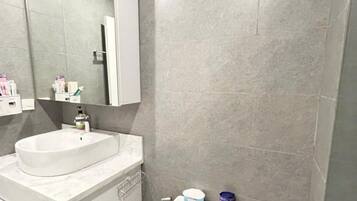 Un baño moderno con lavamanos, espejo y retrete blancos.