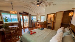 A spacious room with a large bed, a dining area, and a view of the ocean. - Double Waterfront Bungalows (#1 & #4) (Bocas del Toro)