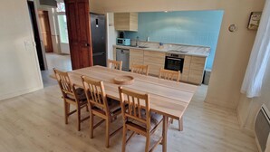 Eine kleine Küche mit modernen Geräten, ein Essbereich mit Holzkästen und Blick ins Freie.