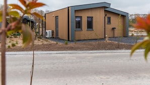 A modern building with a flat roof, large windows, and a small porch area.