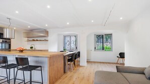 Een moderne keuken met een centraal eiland, barkrukken en een eethoek met stoelen.