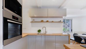 Een moderne keuken met inbouwapparatuur, een houten aanrecht en een klein eiland met een spoelbak.
