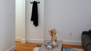 Un salon moderne avec une table basse en bois, un tapis à motifs, une serviette noire posée sur un porte-serviettes fixé au mur et un canapé.