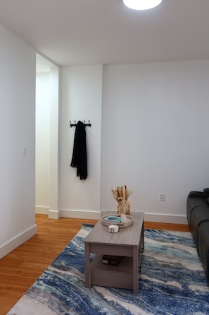 Un salon moderne avec une table basse en bois, un tapis à motifs, une serviette noire posée sur un porte-serviettes fixé au mur et un canapé.