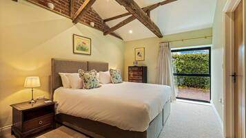 A bedroom with a bed, nightstand, dresser, and a view of a garden through a sliding door.