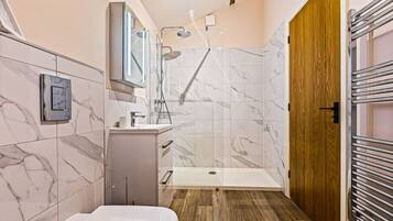 A modern bathroom with a shower, toilet, and sink.