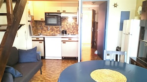A compact kitchen with a microwave, sink, and small refrigerator. There is a dining area with a table and a woven placemat. - Studio with balcony (Six-Fours-les-Plages)