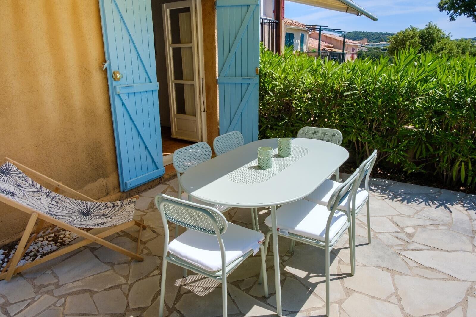 A patio with a white table and chairs, a hammock, and a blue door.