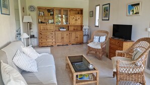 A living room with a sofa, two wicker chairs, a television, a wooden cabinet, and a glass coffee table. - Apartment in Mandelieu-la-Napoule (Mandelieu-la-Napoule)