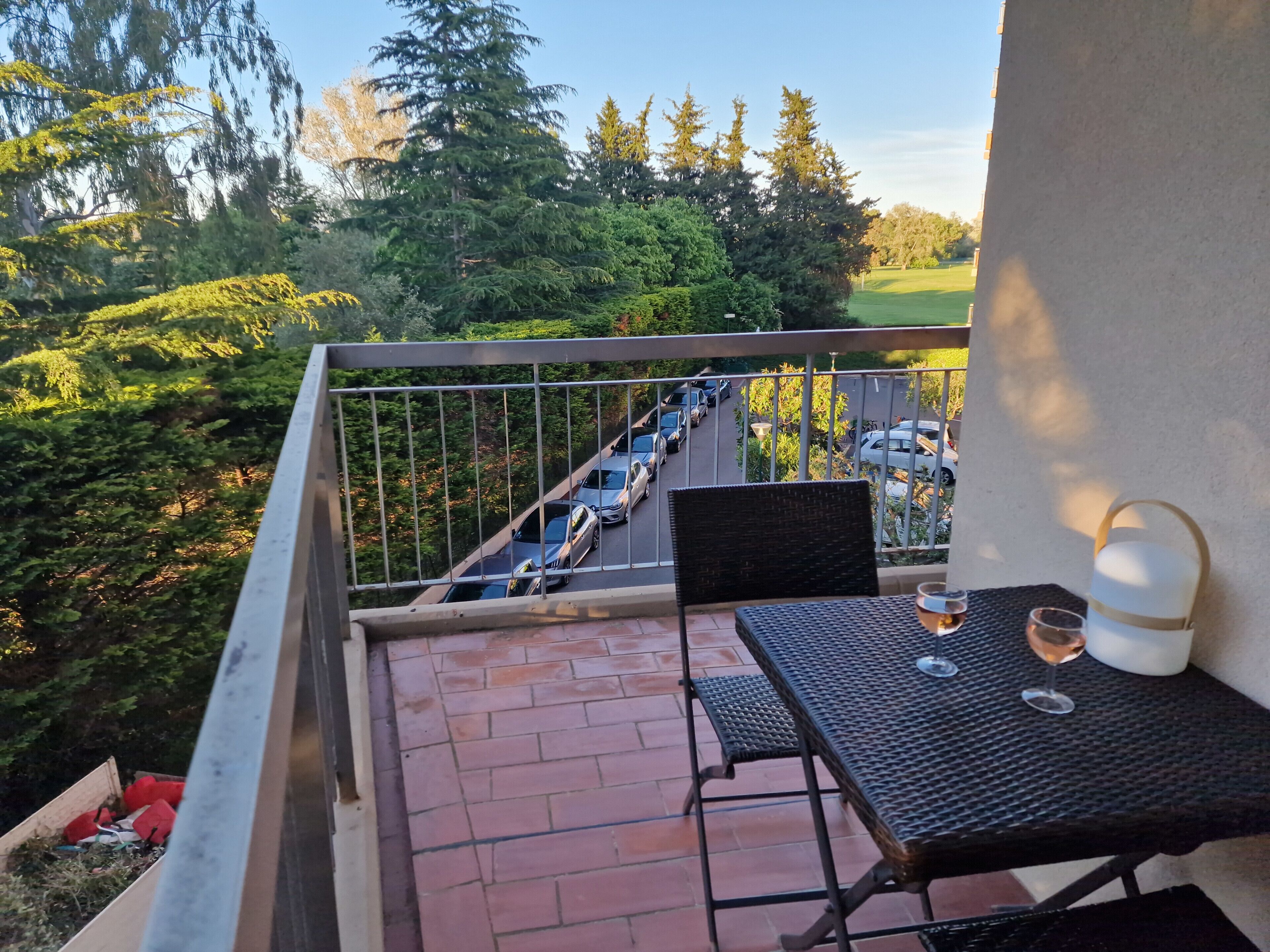 A balcony with a table, two chairs, and a glass of wine.