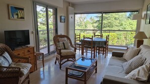 A living room with wicker furniture, a television, a balcony with a table and chairs, and a sofa. - Apartment in Mandelieu-la-Napoule (Mandelieu-la-Napoule)