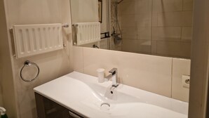 A bathroom with a white sink, a mirror, a shower, and a radiator. - Apartment in Mandelieu-la-Napoule (Mandelieu-la-Napoule)