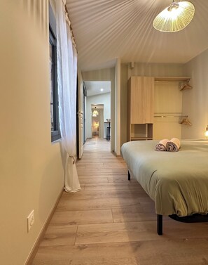 A hotel room with a wooden floor, a bed with green bedding, a hanging light fixture, and a view into the hallway. - House for 8 with garden & terrace in Arcachon (Arcachon)