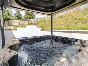 A hot tub with a clear view of the surrounding area, including a wooden fence and greenery. - Brynseion Uchaf (Aberystwyth)