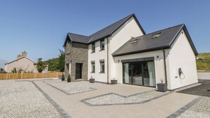 A modern two-story house with a stone facade, large windows, and a gravel driveway. - Brynseion Uchaf (Aberystwyth)