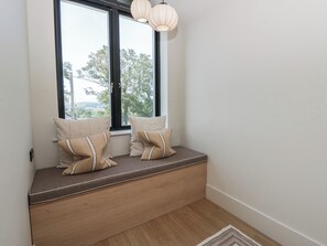 A room with a built-in bench under a window, two pillows, and a hanging light fixture. - Brynseion Uchaf (Aberystwyth)