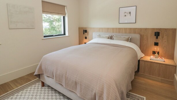 A bedroom with a bed, a bedside table, a window with a view, and a wall-mounted picture. - Brynseion Uchaf (Aberystwyth)