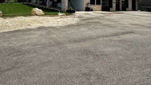 Ein zweistöckiges Gebäude mit einer Sandsteinfassade, einem überdachten Außenbereich und einem Parkplatz.