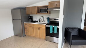 Eine kleine Küche mit Kühlschrank, Mikrowelle, Herd und Holzschränken.