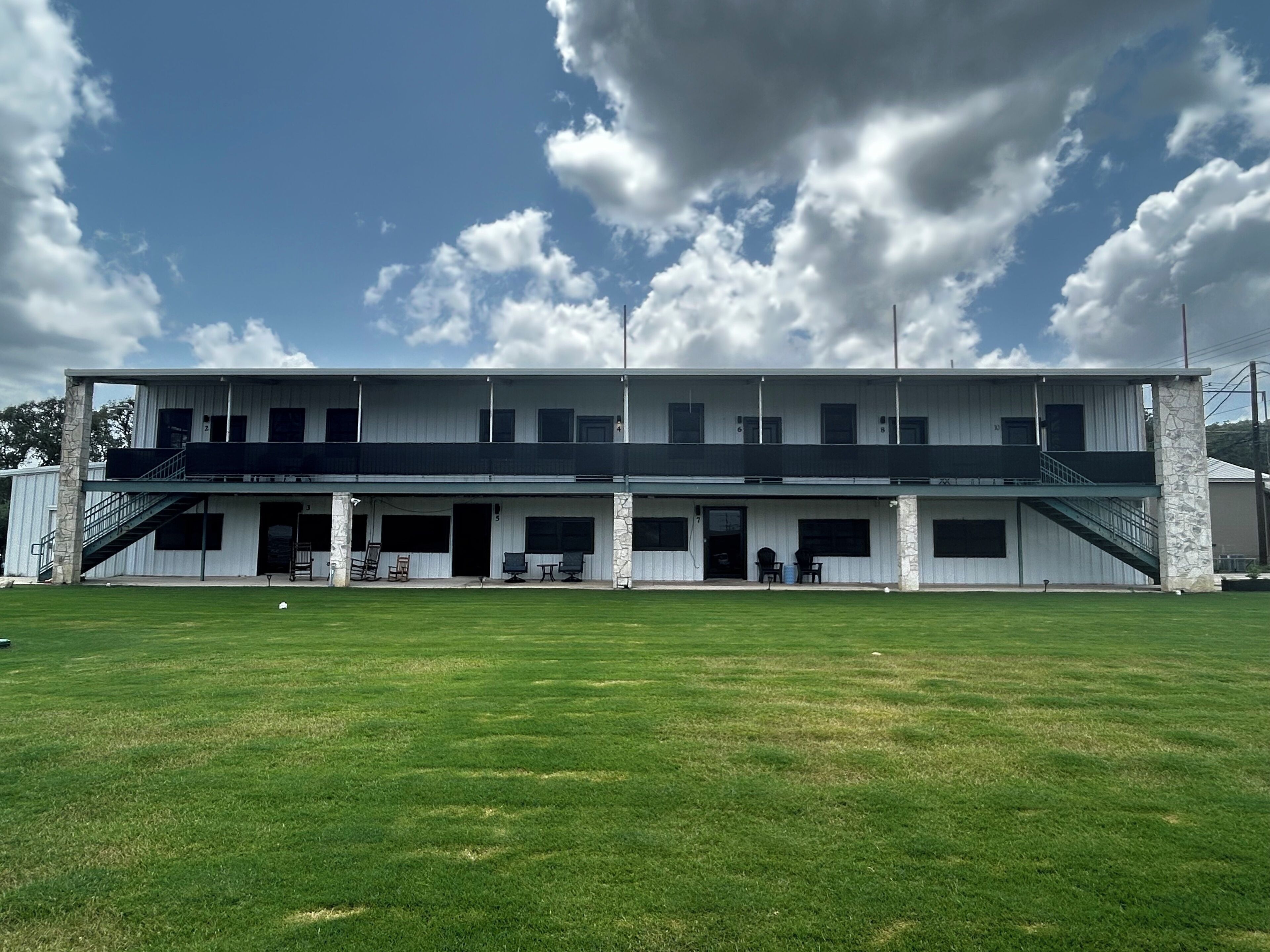 A two-story building with a flat roof, a central staircase, and a covered outdoor seating area.