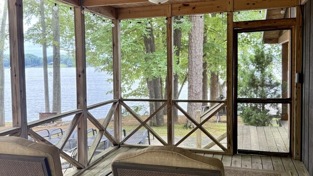 Un espace extérieur abrité, aménagé avec des sièges, et offrant une vue sur un lac et des arbres.