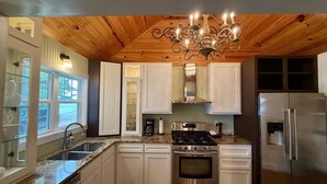 Une cuisine avec un plafond en bois, des appareils électroménagers en acier inoxydable et un meuble avec une porte en verre.
