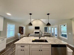 A spacious kitchen with granite countertops, a built-in dishwasher, and pendant lighting.