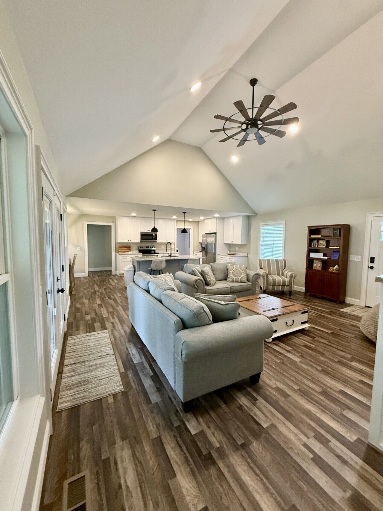 A spacious living area with a high ceiling, a built-in kitchen, and a cozy seating arrangement.
