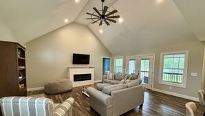 A spacious living room with a fireplace, a television, and a large window. - The Shakonohey on Weiss Lake (Centre)