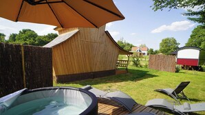 A backyard with a hot tub, lounge chairs, and a wooden deck. - The Hobbit House at the Crossroads (Fontenoy)