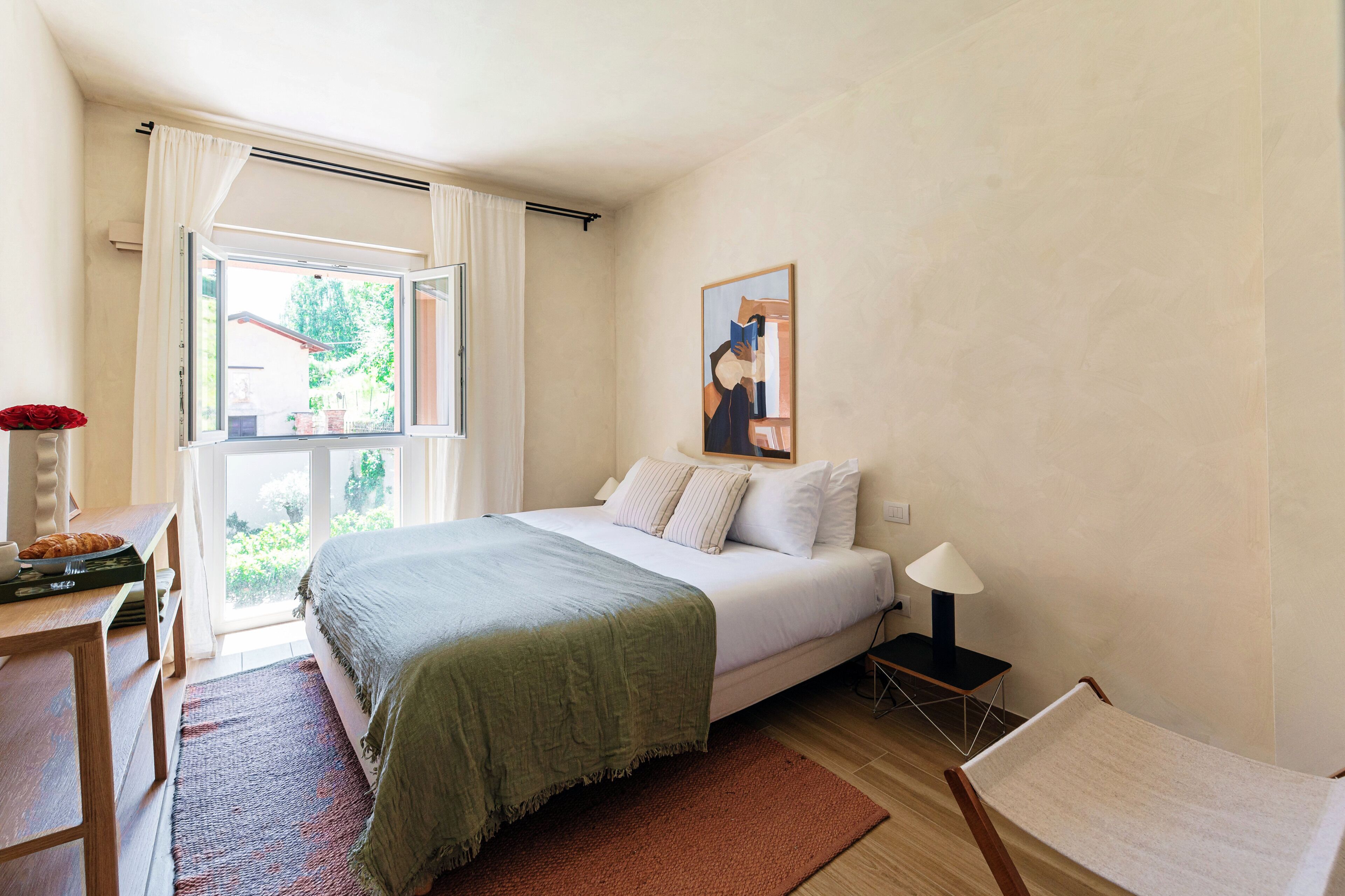 Un dormitorio con una cama, un escritorio, una silla, una lámpara y una ventana.