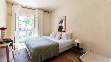 Un dormitorio con una cama, un escritorio, una silla, una lámpara y una ventana.