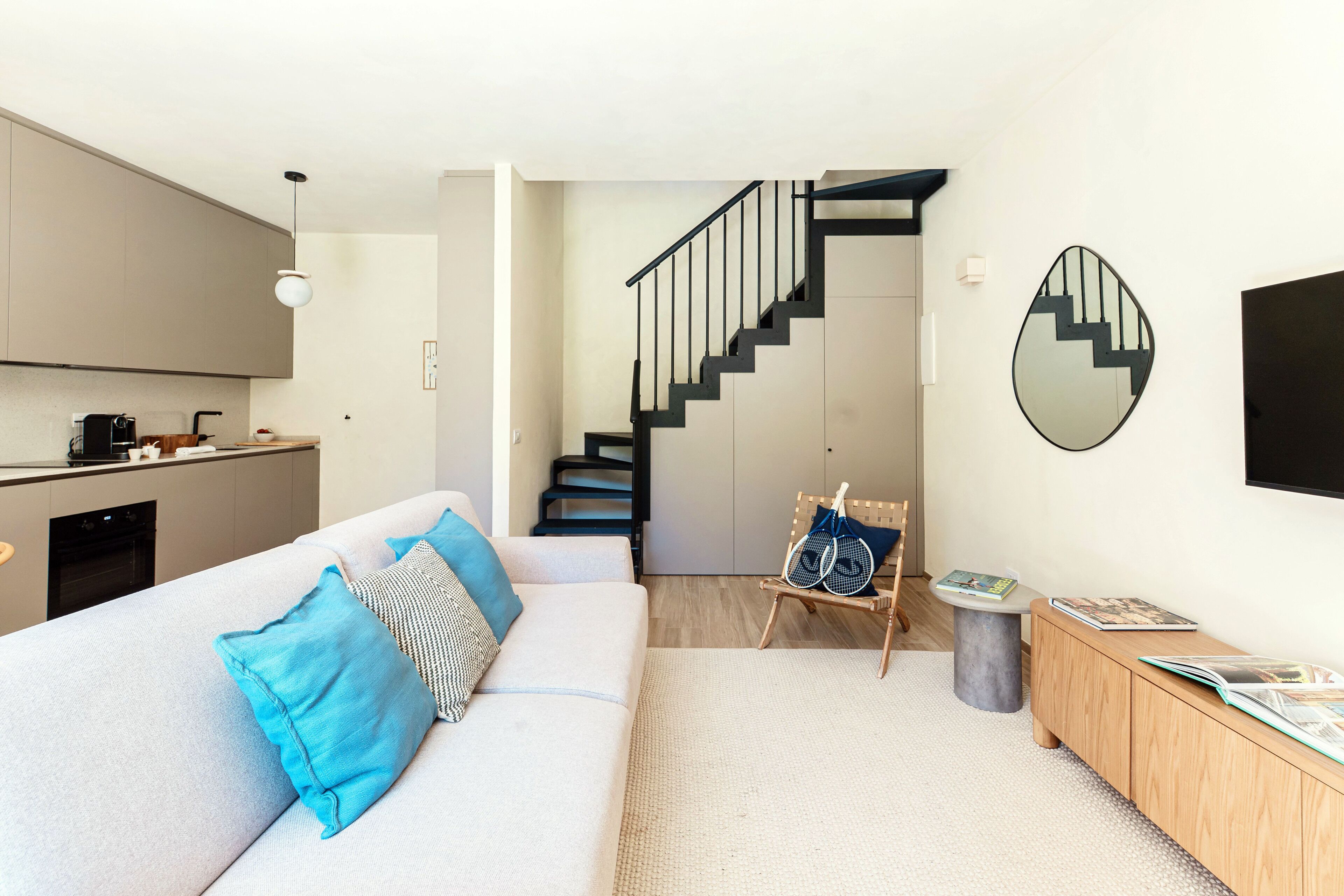 Ein modernes Wohnzimmer mit Sofa, Couchtisch, einer Treppe und einem Küchenbereich.