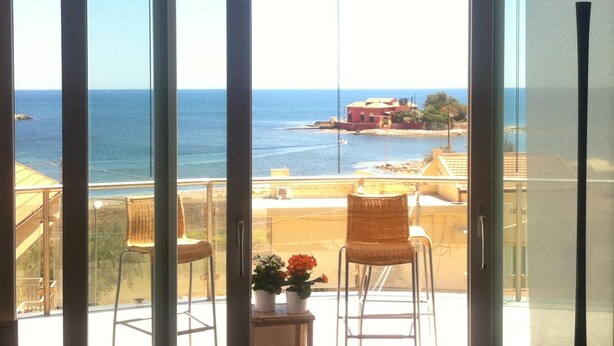 Ein Balkon mit Blick auf das Meer und ein Gebäude gegenüber.