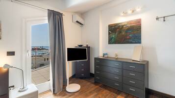 Ein modernes Badezimmer mit Holzboden, einem grauen Schrank, einem Flachbildfernseher und einem Bild an der Wand.