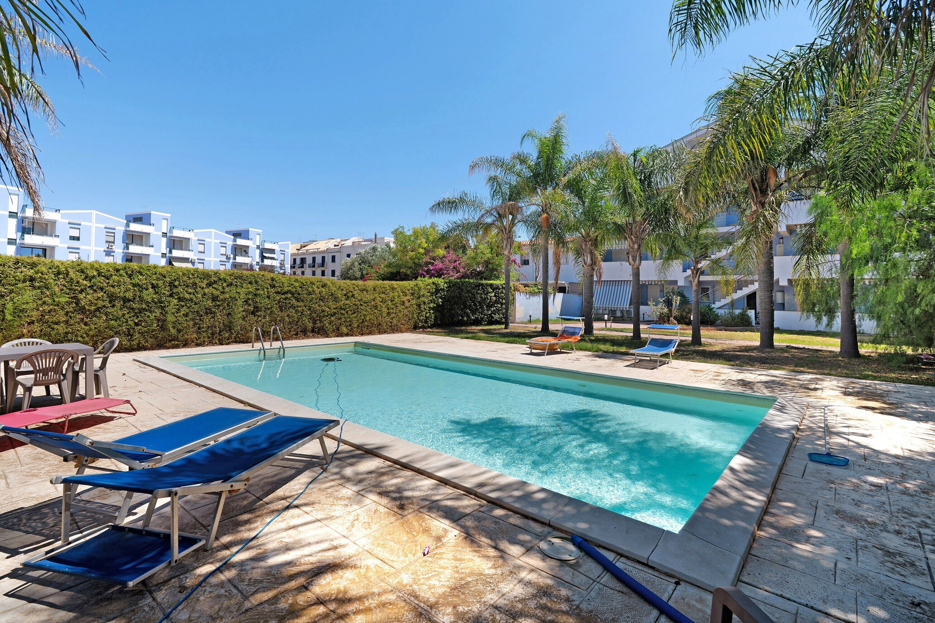 A swimming pool with lounge chairs and a clear sky.