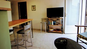 Una sala de estar con televisor, una mesa de comedor y dos sillas.
