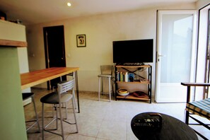 Ein Wohnzimmer mit Fernseher, einem Esstisch und zwei Stühlen.